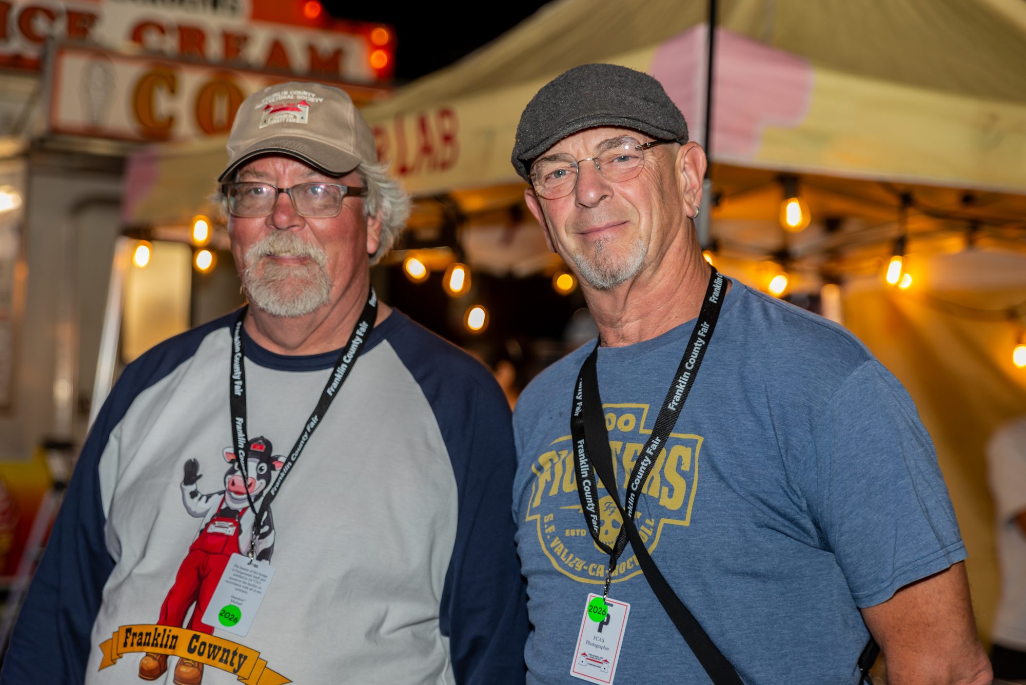 Two fair volunteers smiling under string lights at night
